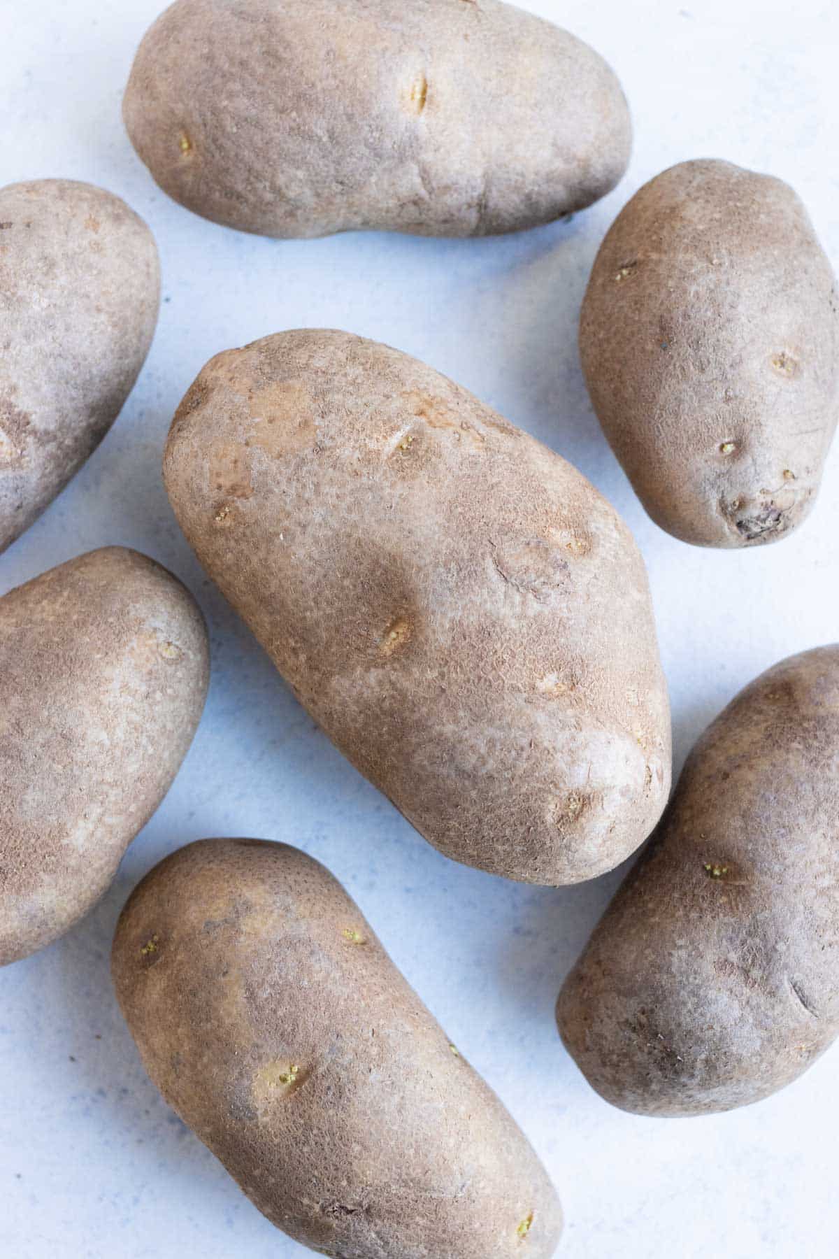 Multiple potatoes sitting on the countertop.
