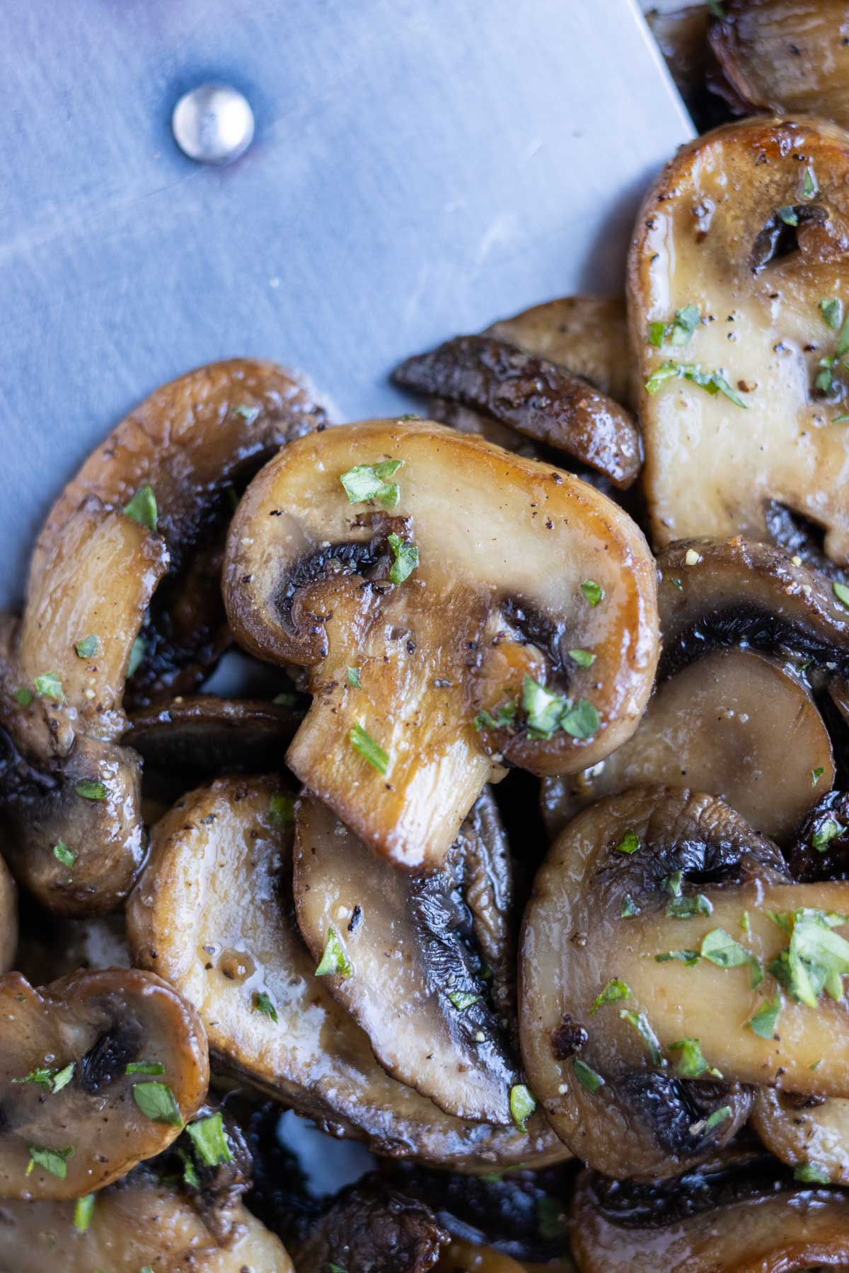 A closeup shot of mushrooms being cooked in a skillet.