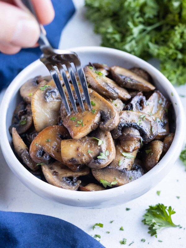 A white bowl full of healthy and delicious sauteed mushrooms.