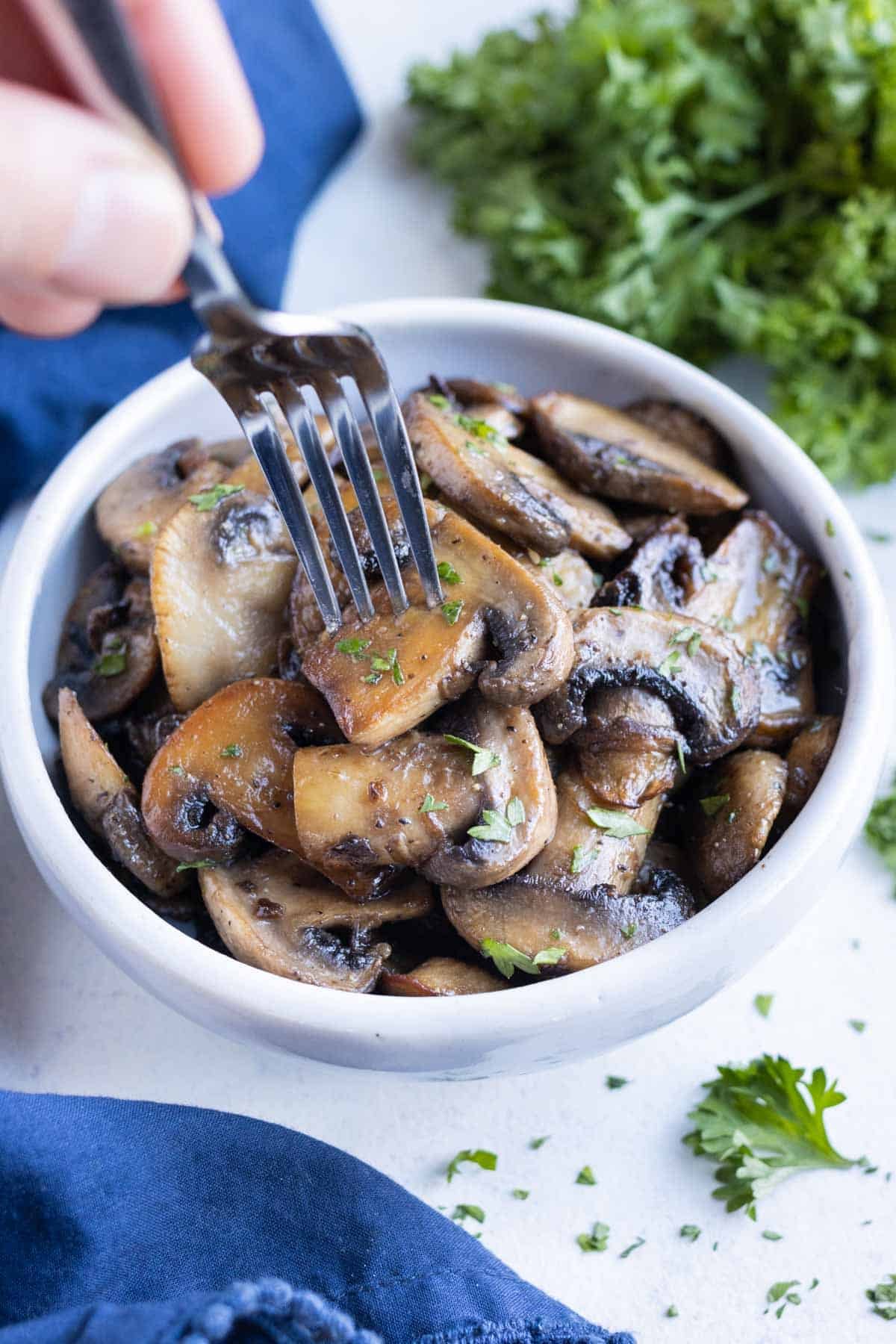 A white bowl full of healthy and delicious sauteed mushrooms.