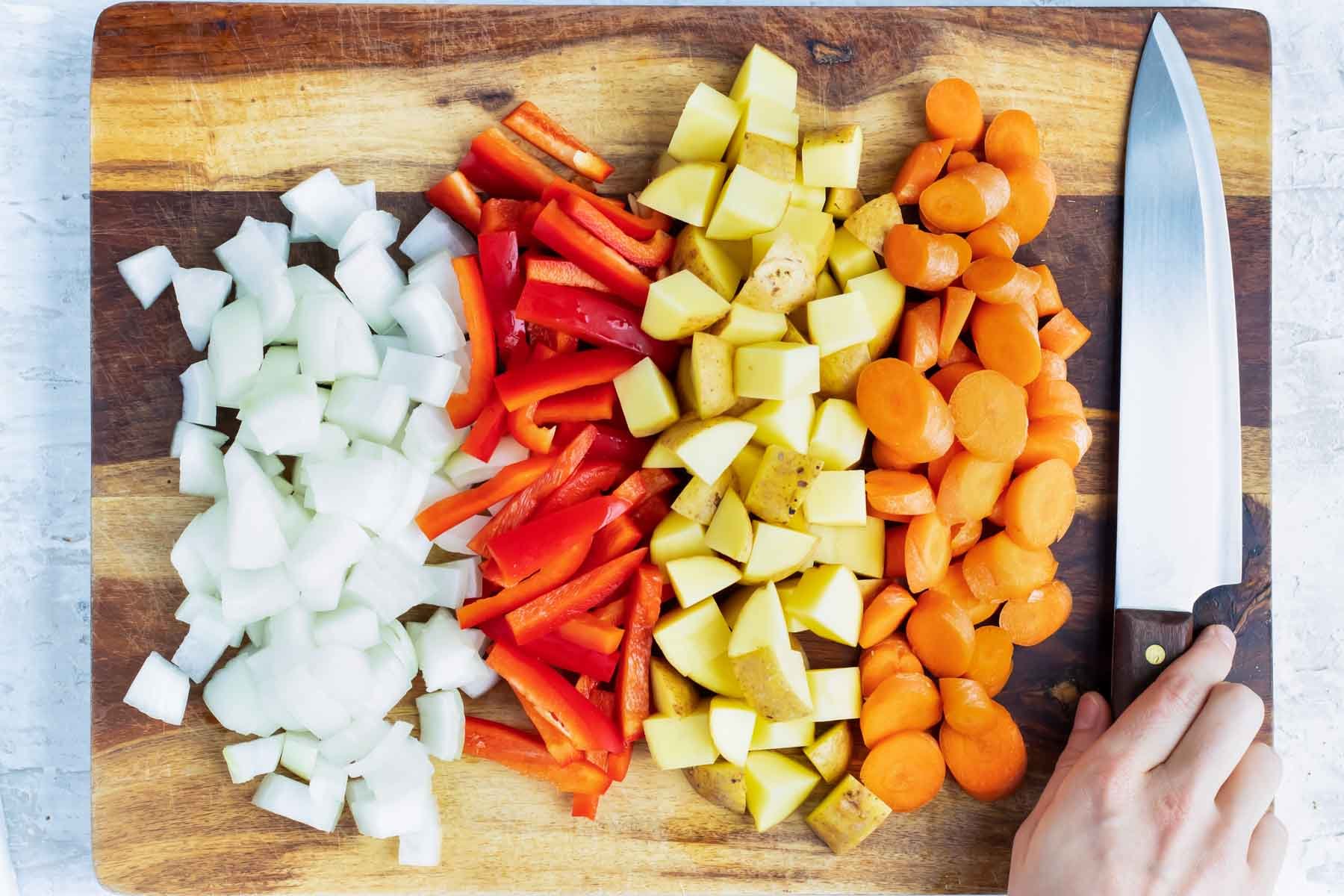 Onion, red bell pepper, Yukon gold potatoes, and carrots as ingredients in a yellow chicken curry recipe.