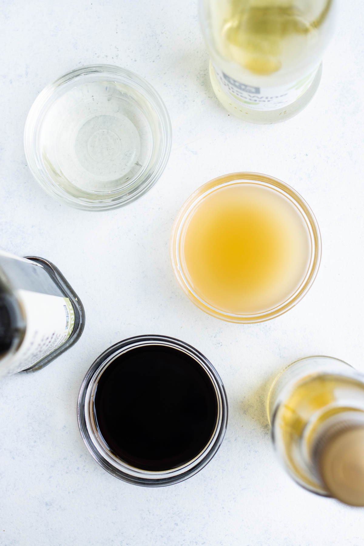 Three small, clear glass bowls filled with different types of vinegars.