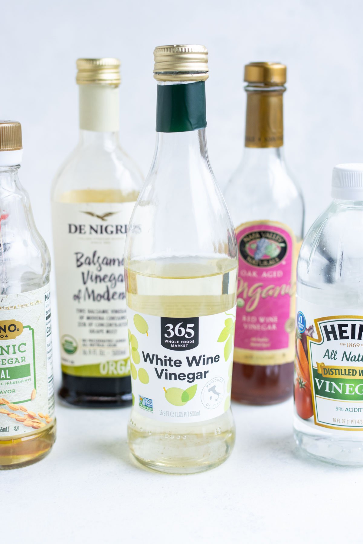 Zoomed-in white wine vinegar surrounded by other assorted vinegars.