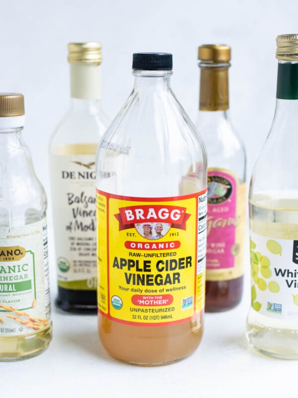 Apple cider vinegar centered with assorted vinegars surrounding it.