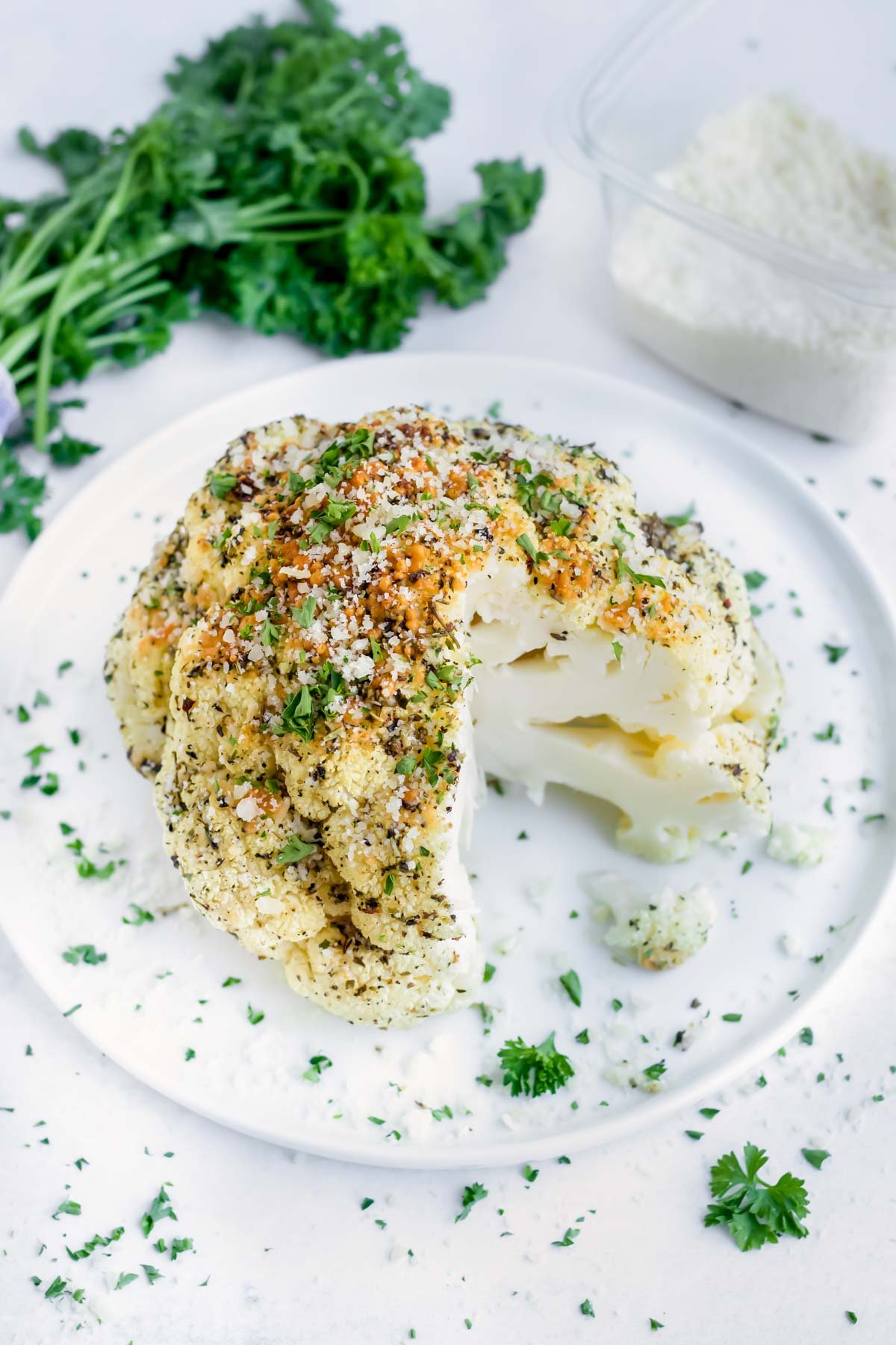 A gluten-free and low-carb roasted cauliflower head on a white plate.
