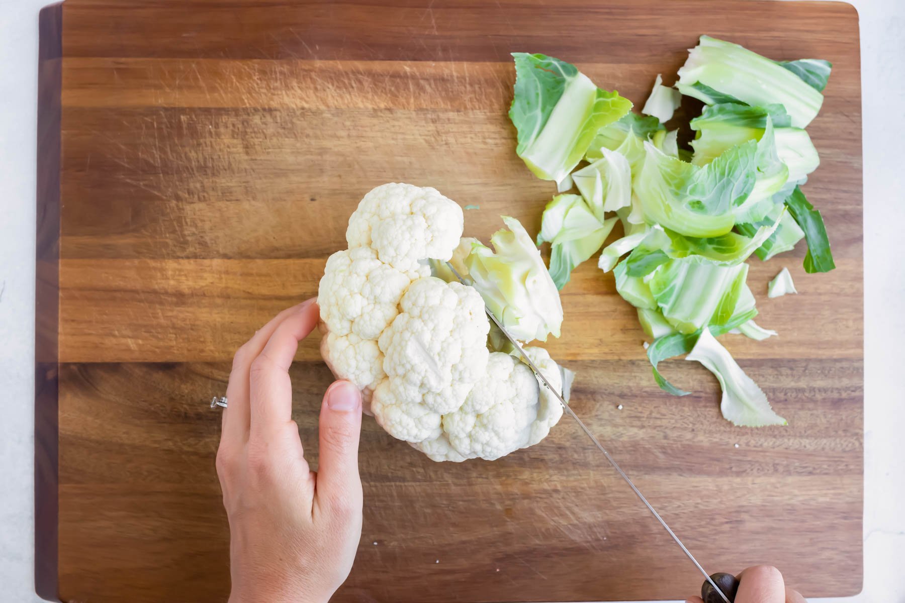 The stem and leaves are taken off of the cauliflower before being baked in the oven.