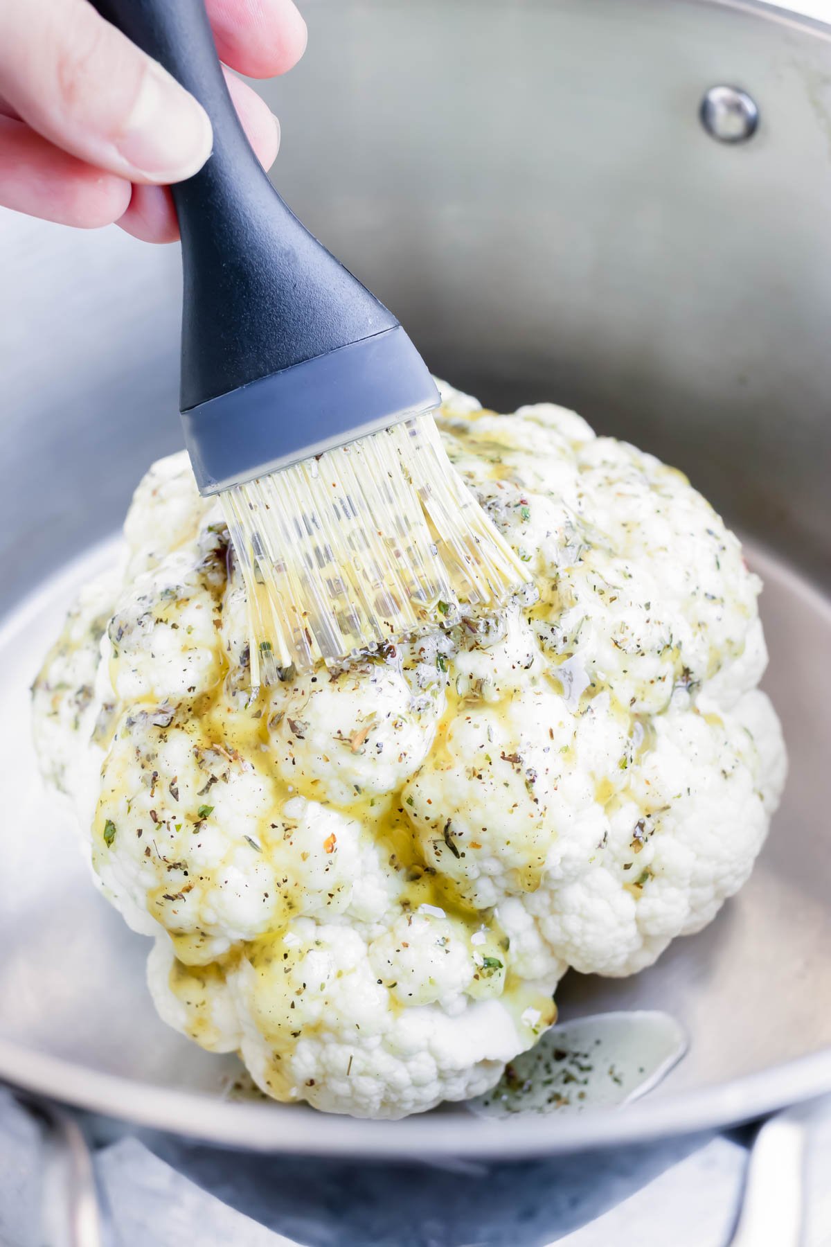 Whole baked cauliflower is brushed with a garlic herb butter.