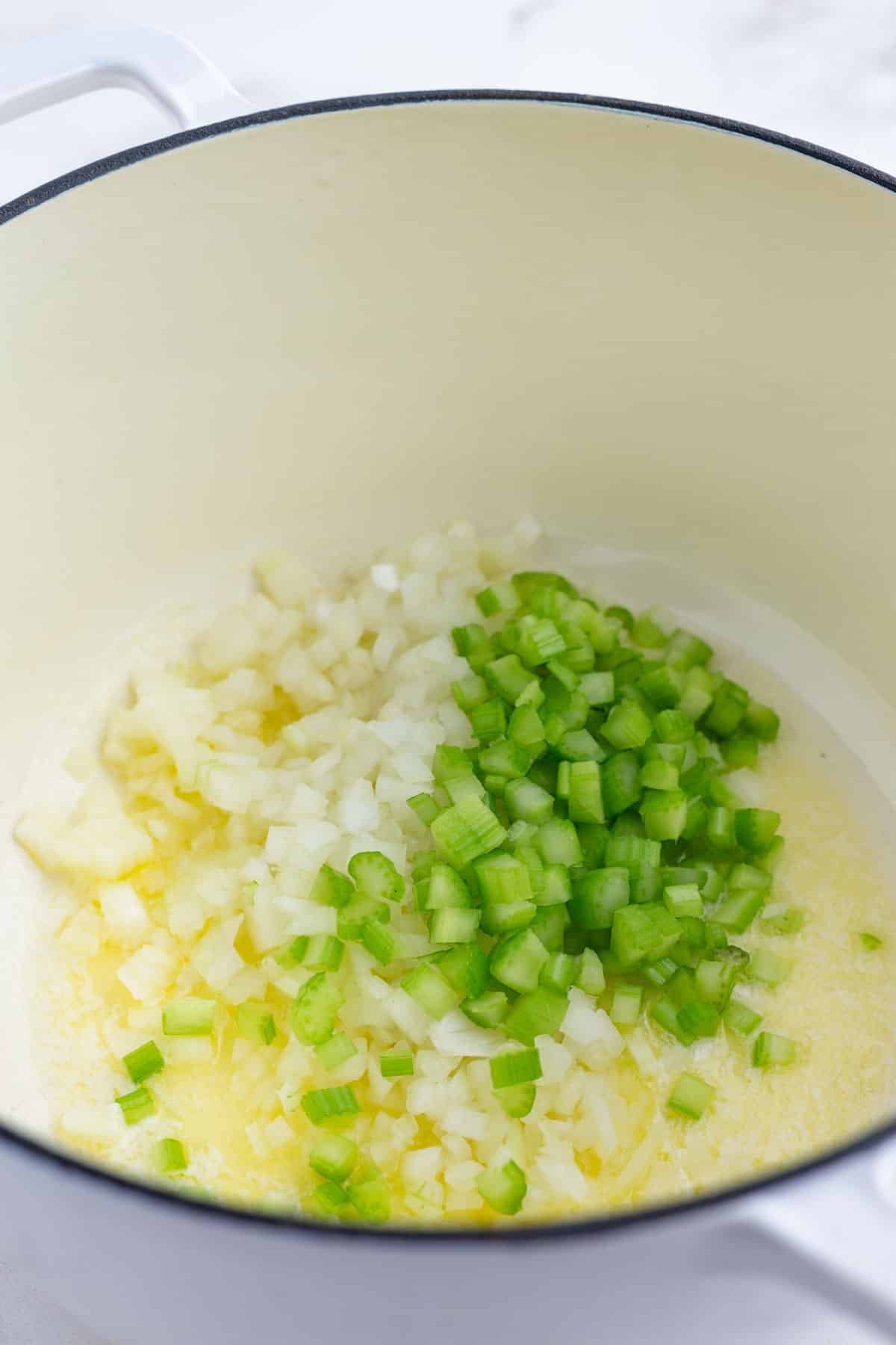 Celery, onion, and butter are heated in a pan.