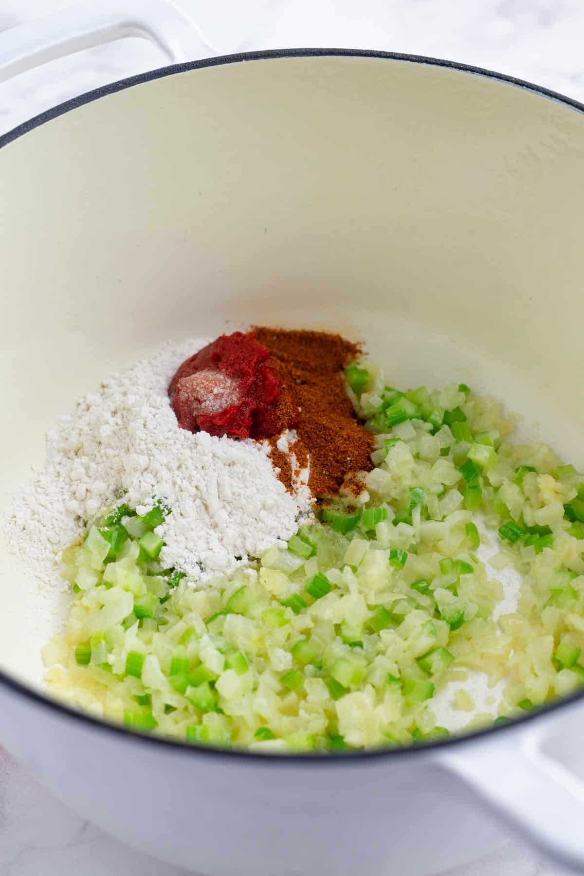 Flour, seasonings, and tomato paste is added to the onion, garlic, and celery base.