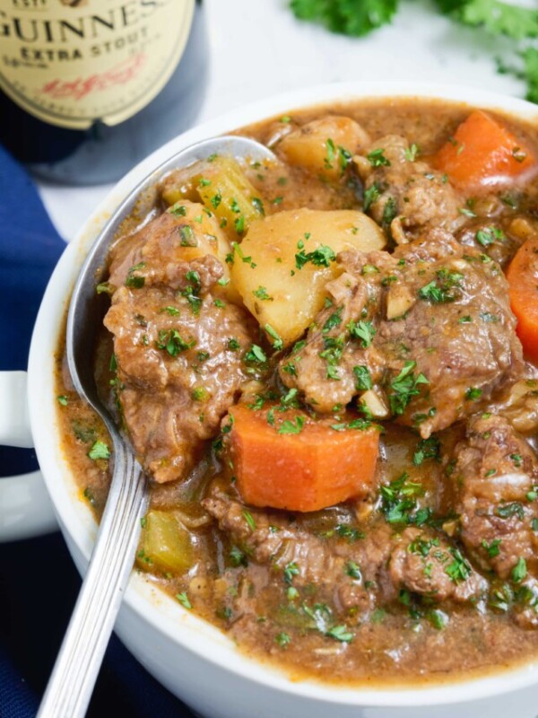 Beef stew is eaten with a metal spoon from a bowl.