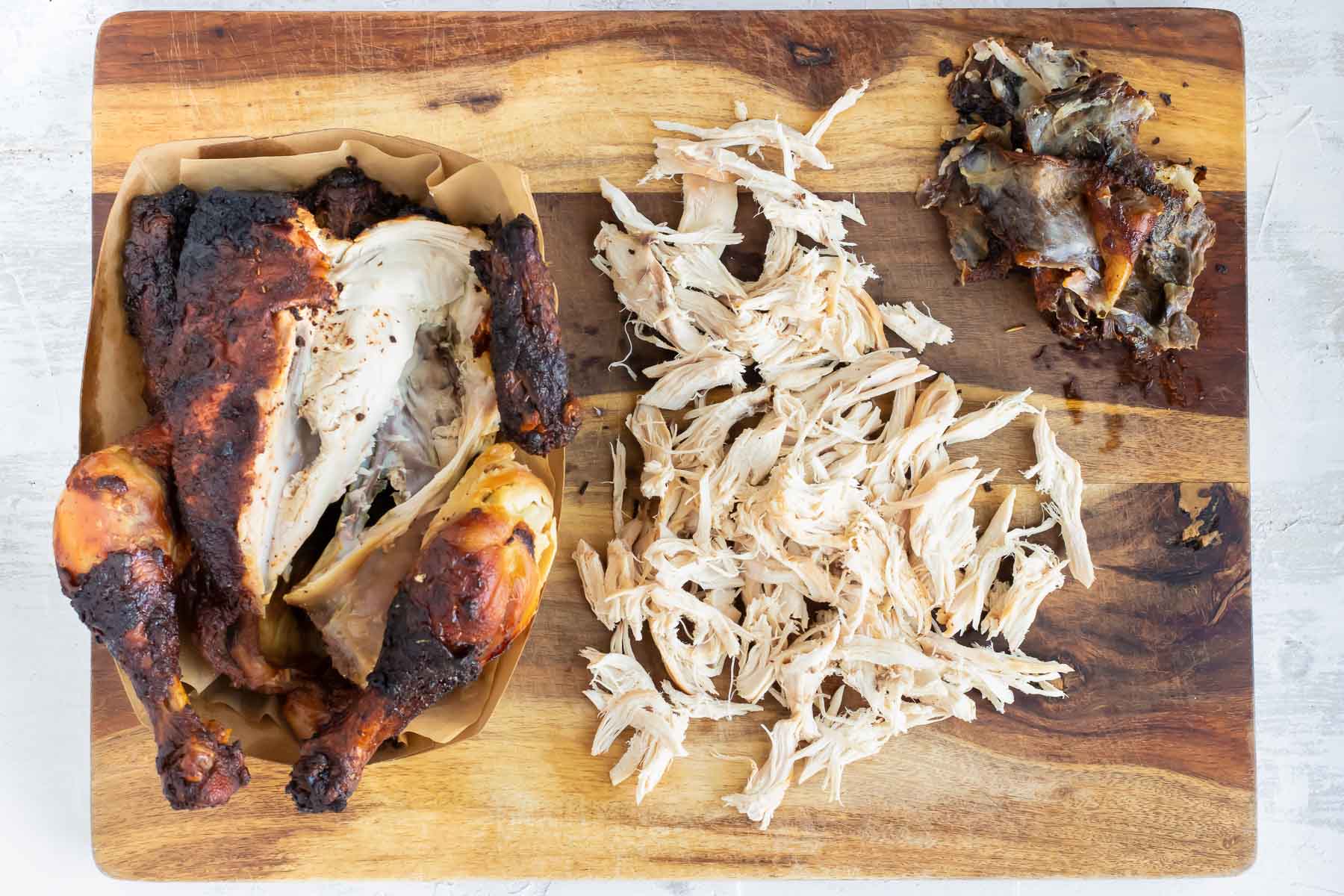 A rotisserie chicken that has been shredded on a wooden cutting board for a lettuce wraps recipe.