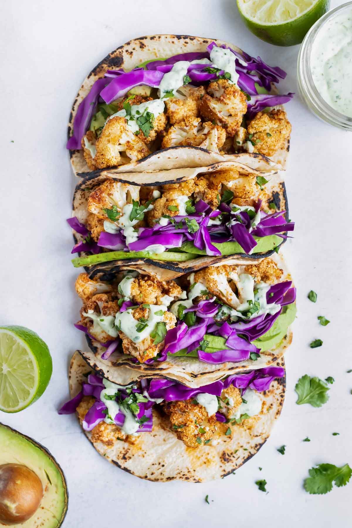 A row of vegetarian tacos made with a homemade seasoning mix and a cilantro lime cream sauce.