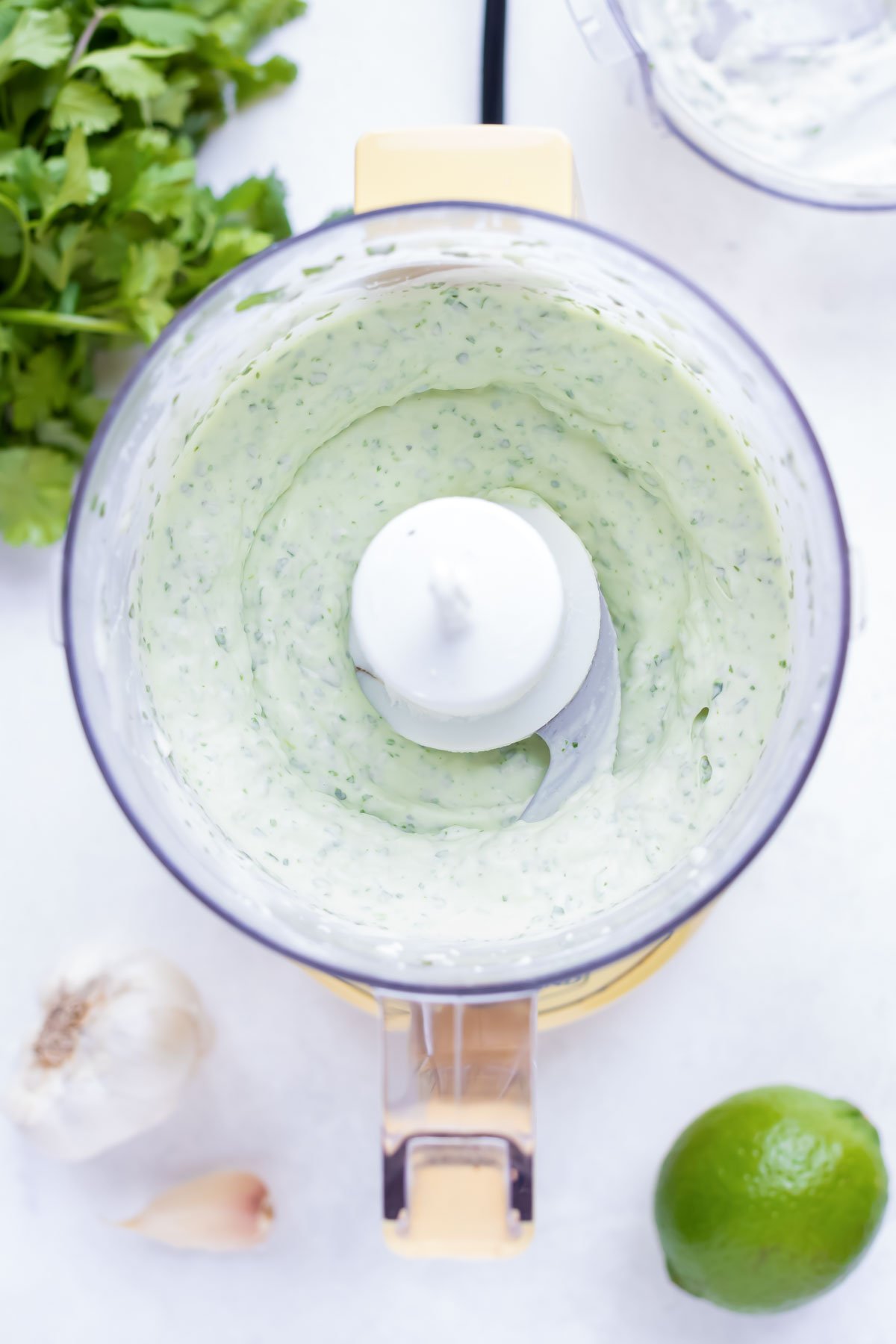 A food processor full of a vegan cilantro cream sauce for tacos.