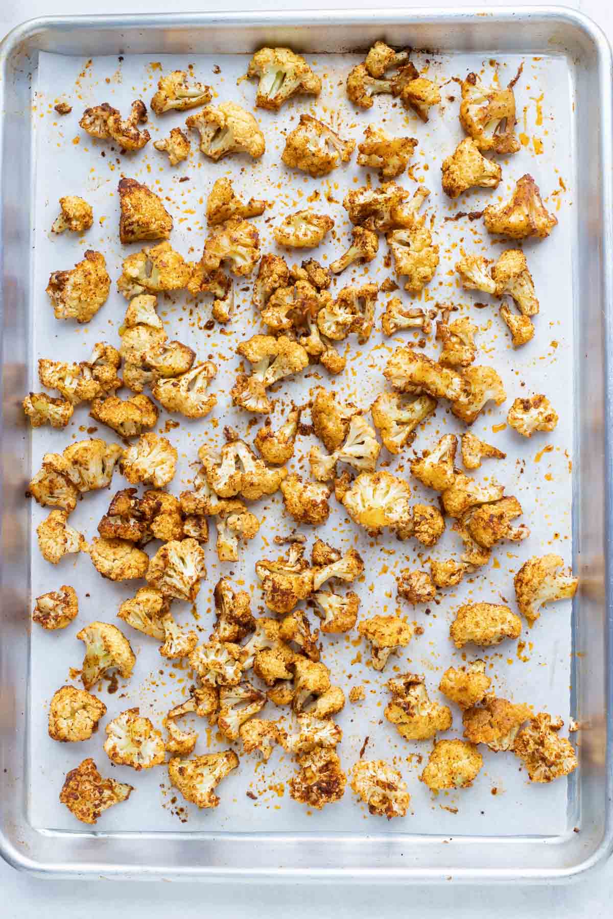 Taco seasoning coated cauliflower on a baking sheet with parchment paper.
