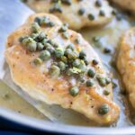 Lemon Chicken Piccata with capers and a creamy sauce in a skillet.