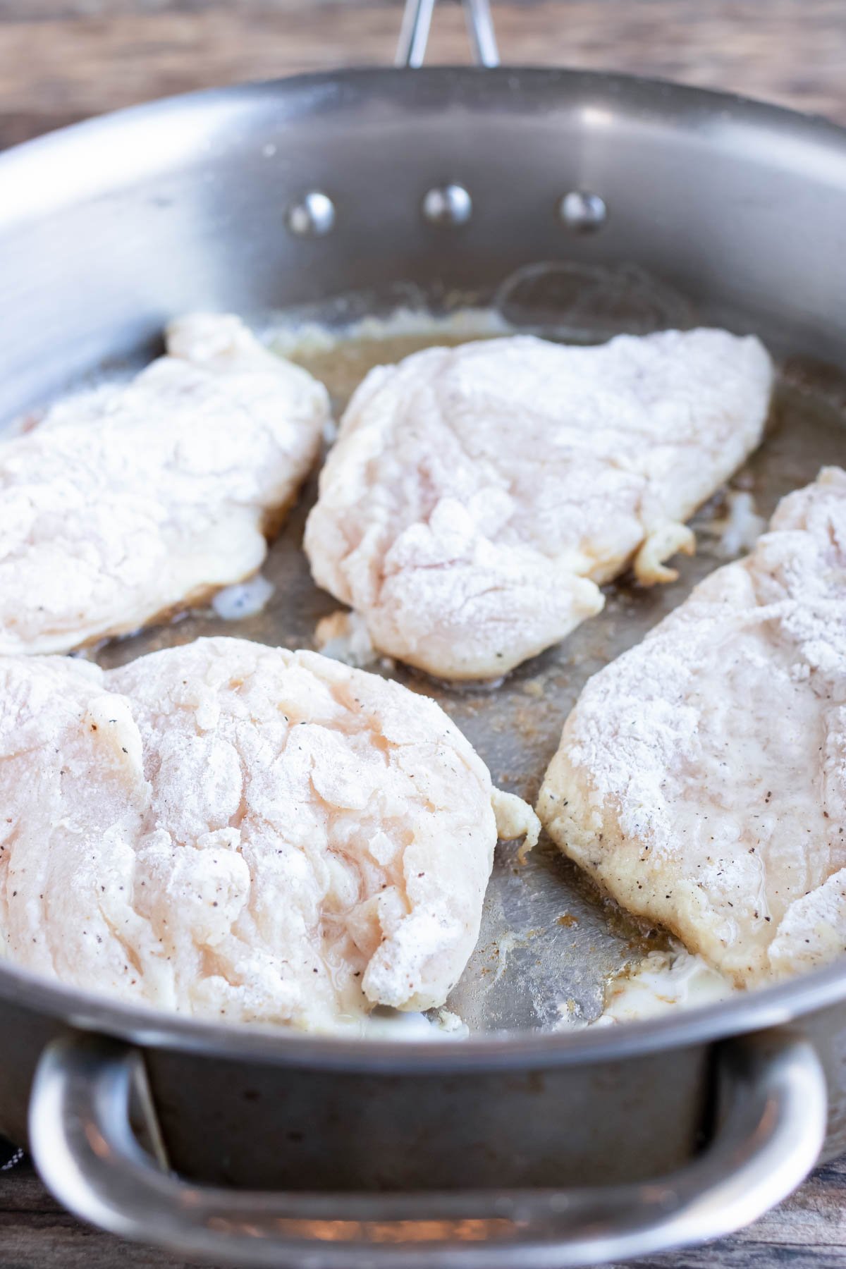 Dredged chicken breasts are added to the hot butter.