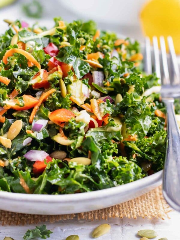 A massaged kale salad with avocado in a white bowl.