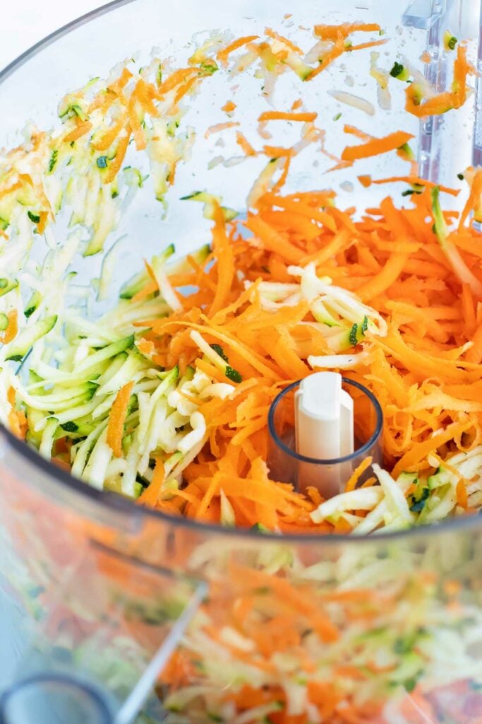Shredded zucchini and carrots in a food processor.