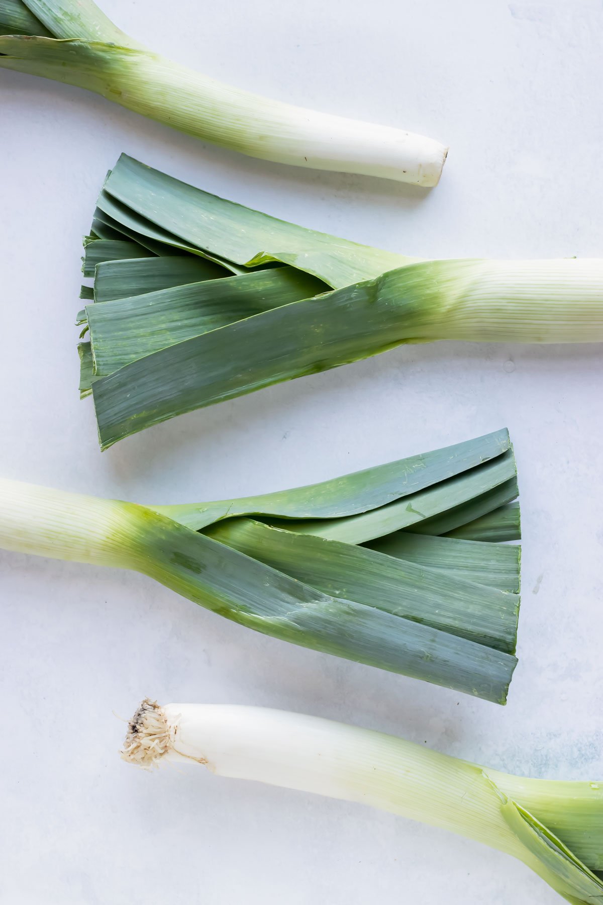 Four leeks on a white countertop.