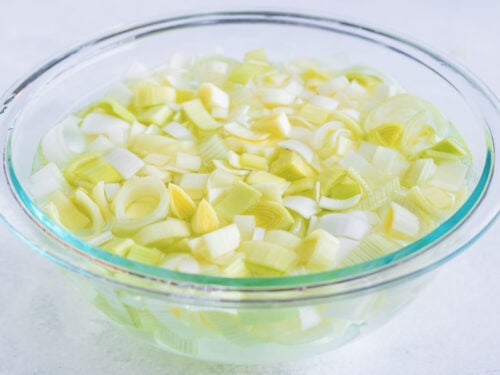 A bowl full of water showing how to clean leeks.