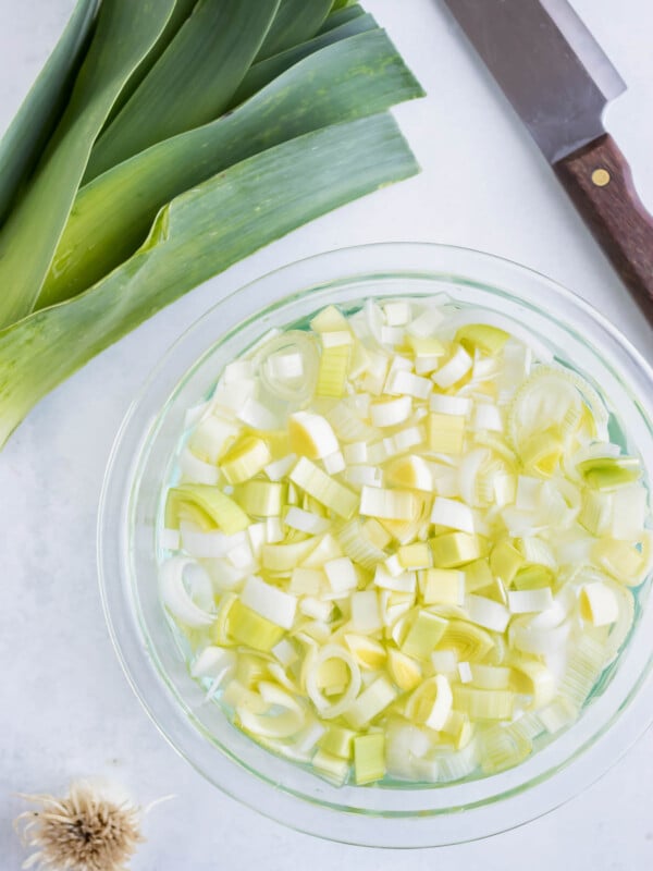 Fresh leeks that have been cut and are being cleaned in a bowl of water.