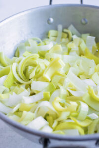 A colander full of thinly sliced and cleaned leeks for a potato leek soup recipe.