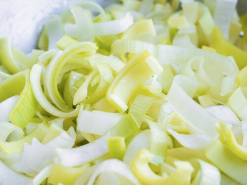 A colander full of thinly sliced and cleaned leeks for a potato leek soup recipe.