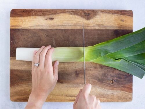 The green leaves of a leek being cut off and discarded.