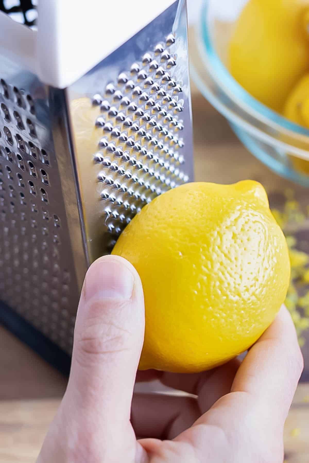 Demonstrating how to use a boxed cheese grater to zest a lemon.