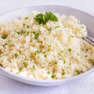Instant couscous in a grey bowl with parsley sprinkled on top.