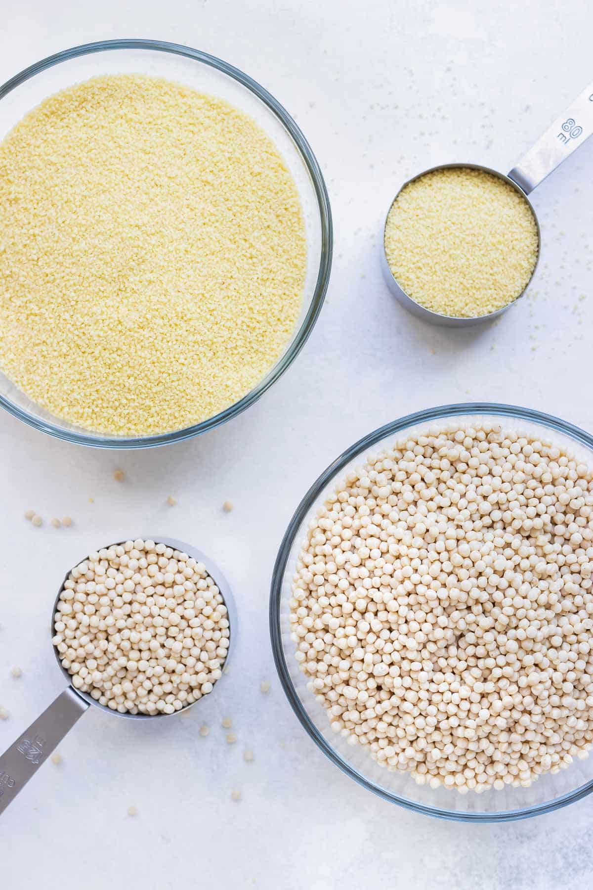 Two types of couscous in glass bowls with measuring cups next to them.