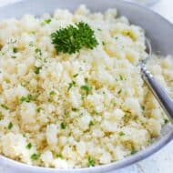 Instant couscous in a grey bowl with parsley sprinkled on top.