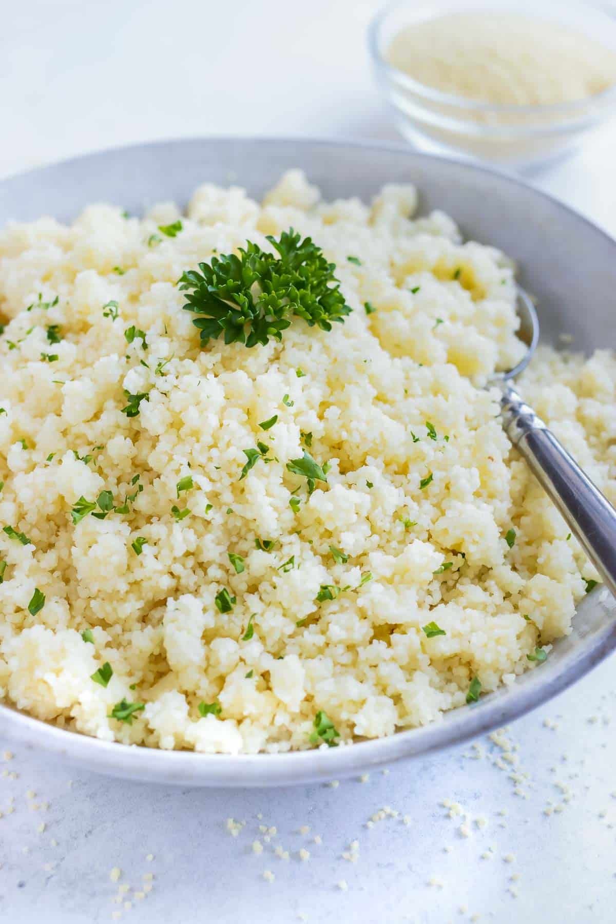 Instant couscous in a grey bowl with parsley sprinkled on top.