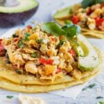 Two migas tacos on a white background with an avocado.