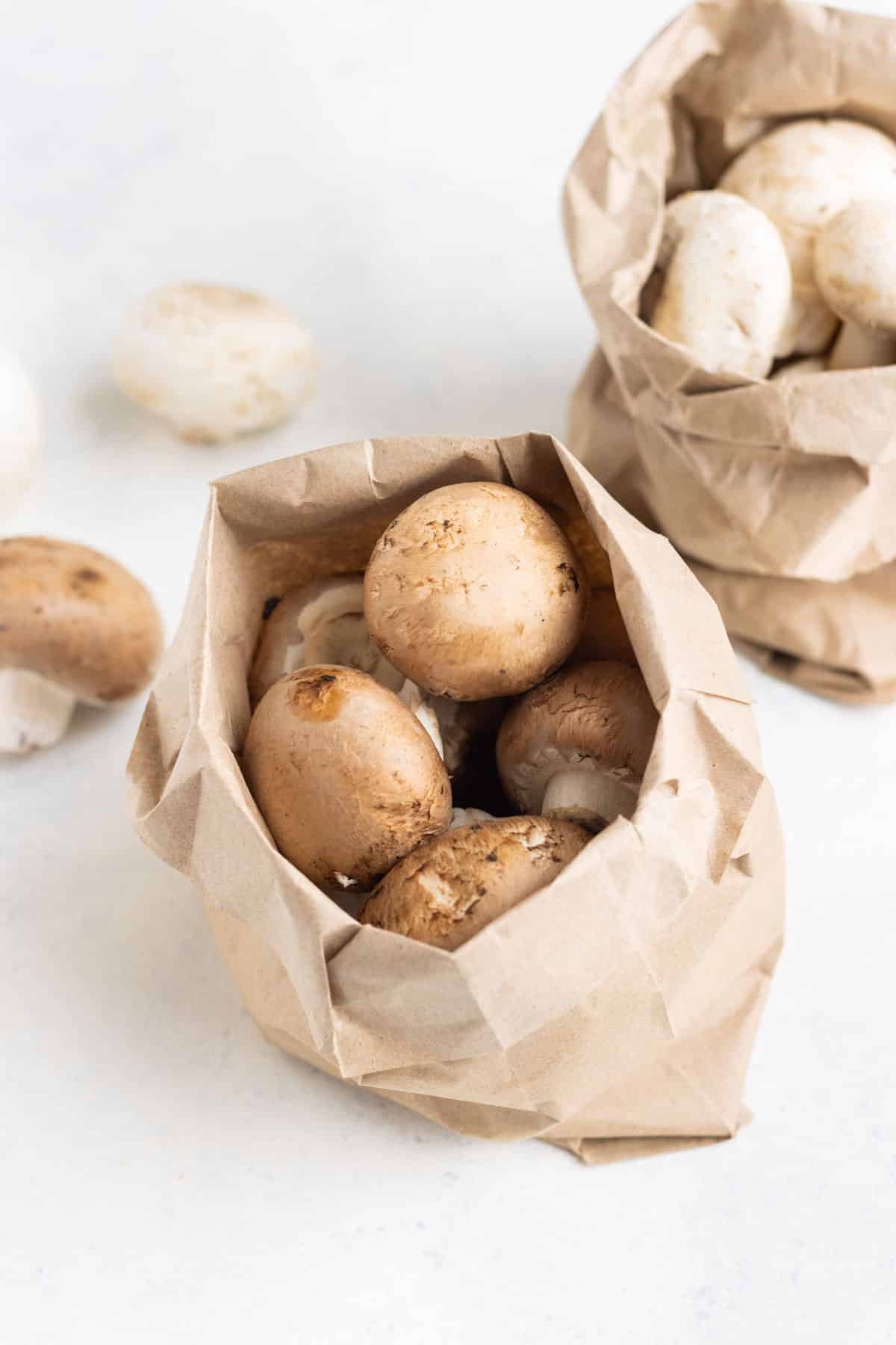 A brown paper bag of whole mushrooms on the countertop.