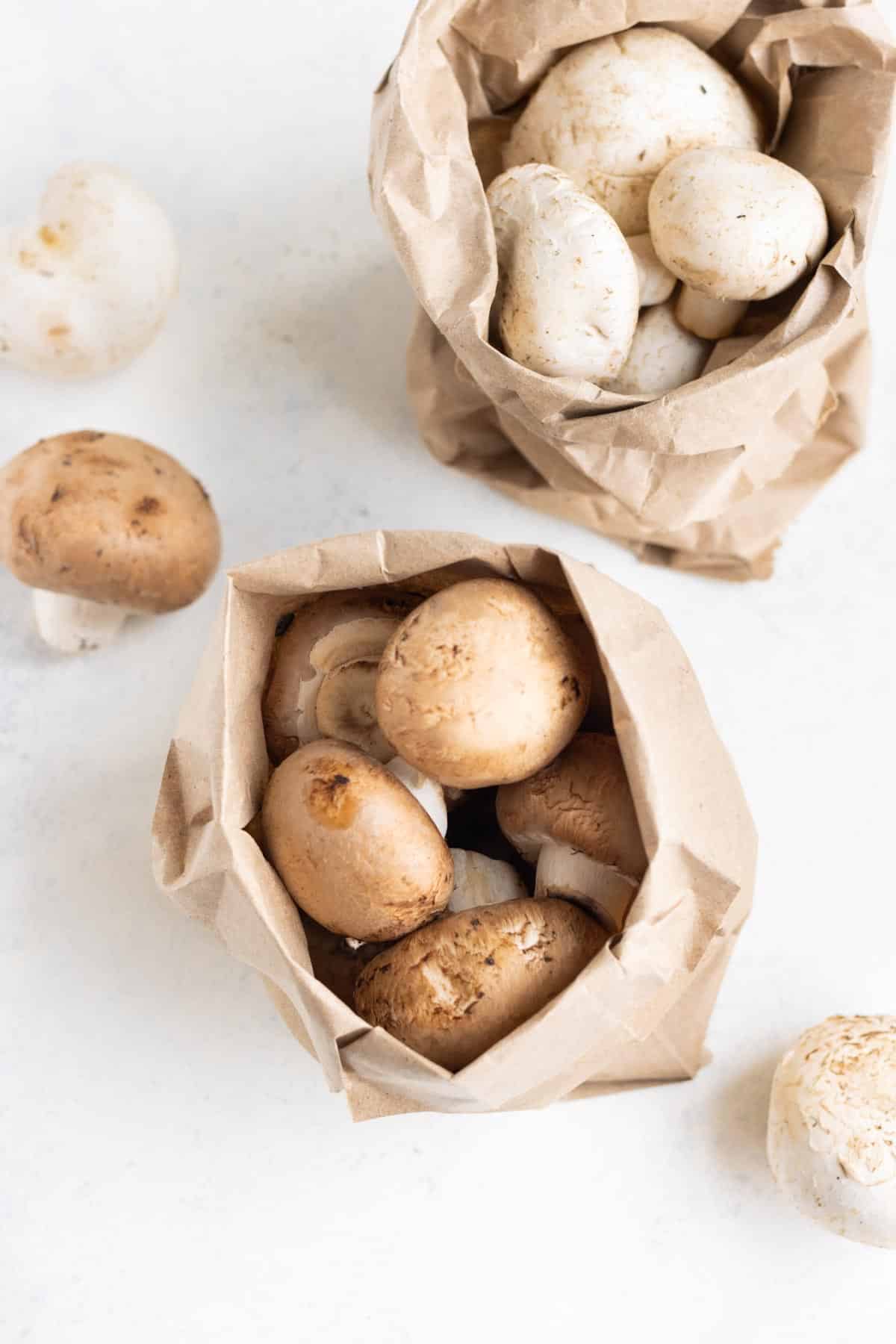 A brown paper bag of whole mushrooms on the countertop.