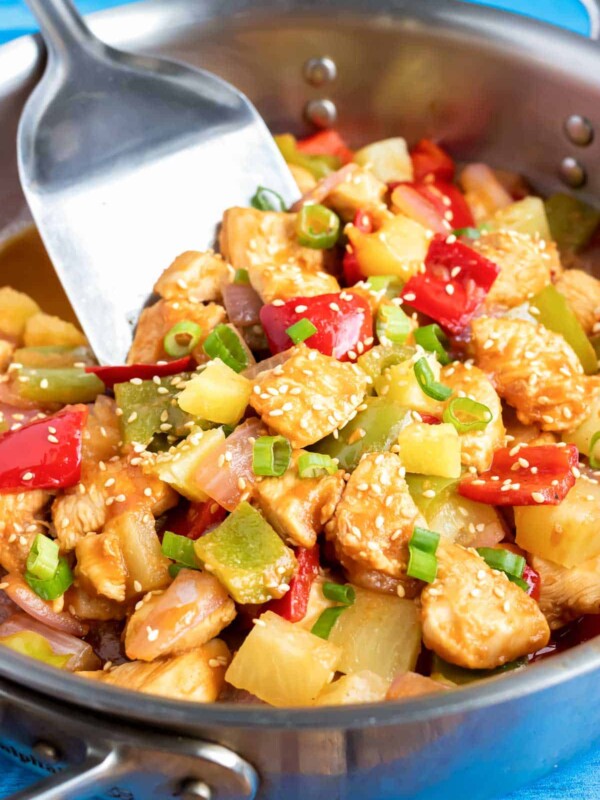 A skillet full of cubed chicken and vegetables in a sticky pineapple sauce.
