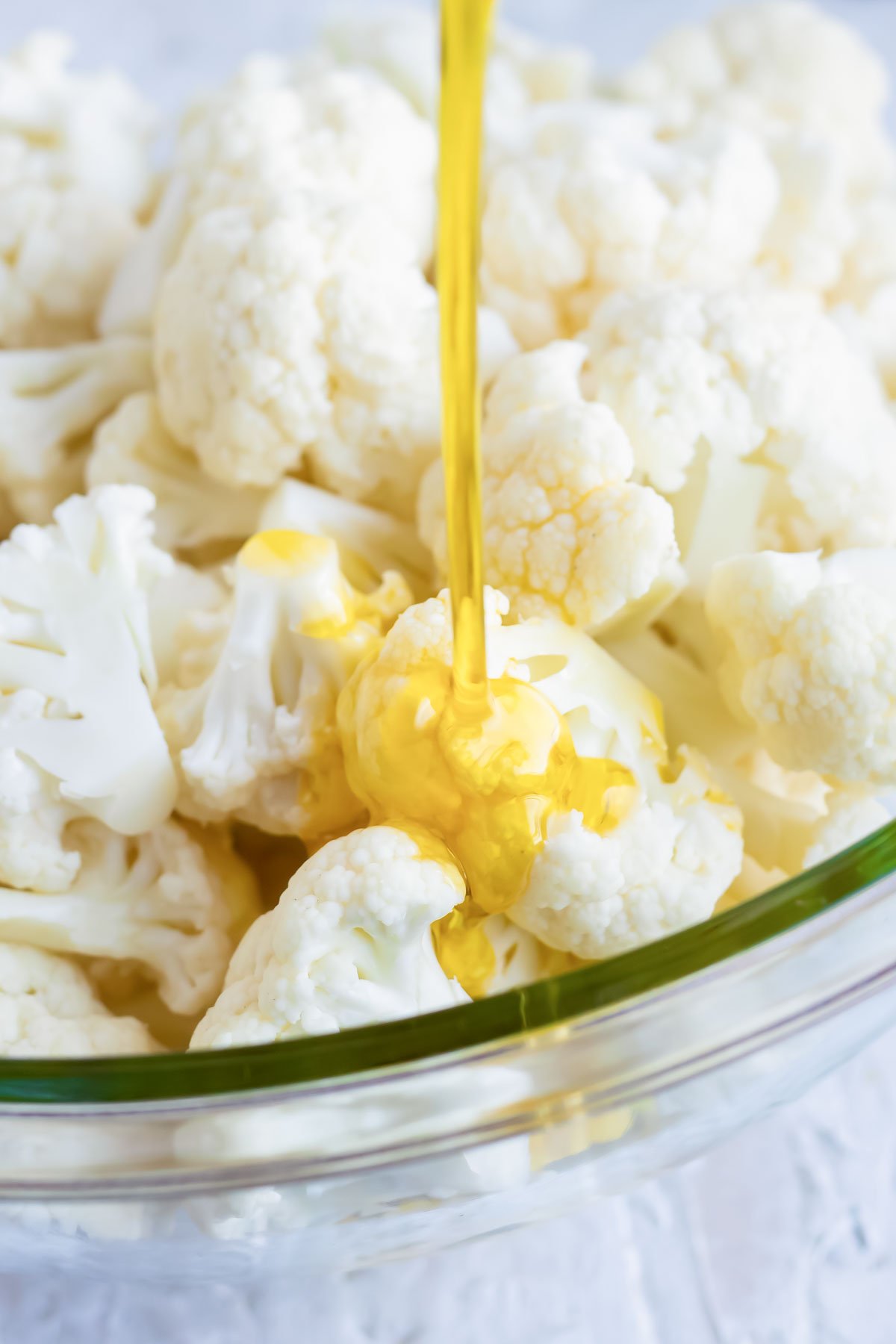 Olive oil being poured on to cauliflower florets before roasting in the oven.