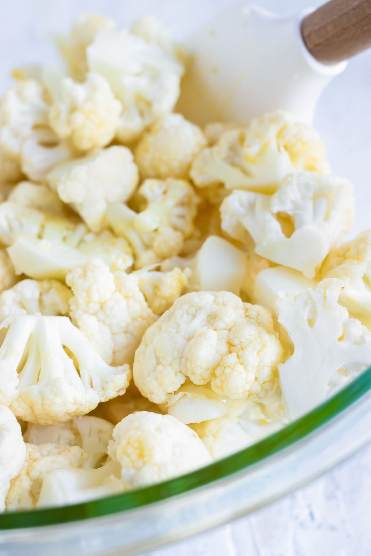 Cauliflower being tossed in olive oil showing how to roast cauliflower.