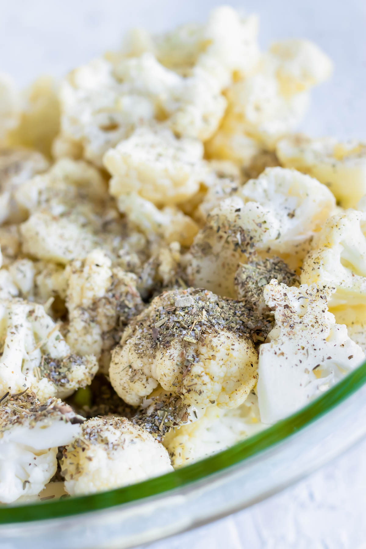 Cauliflower florets in a large bowl with Italian seasoning mix.
