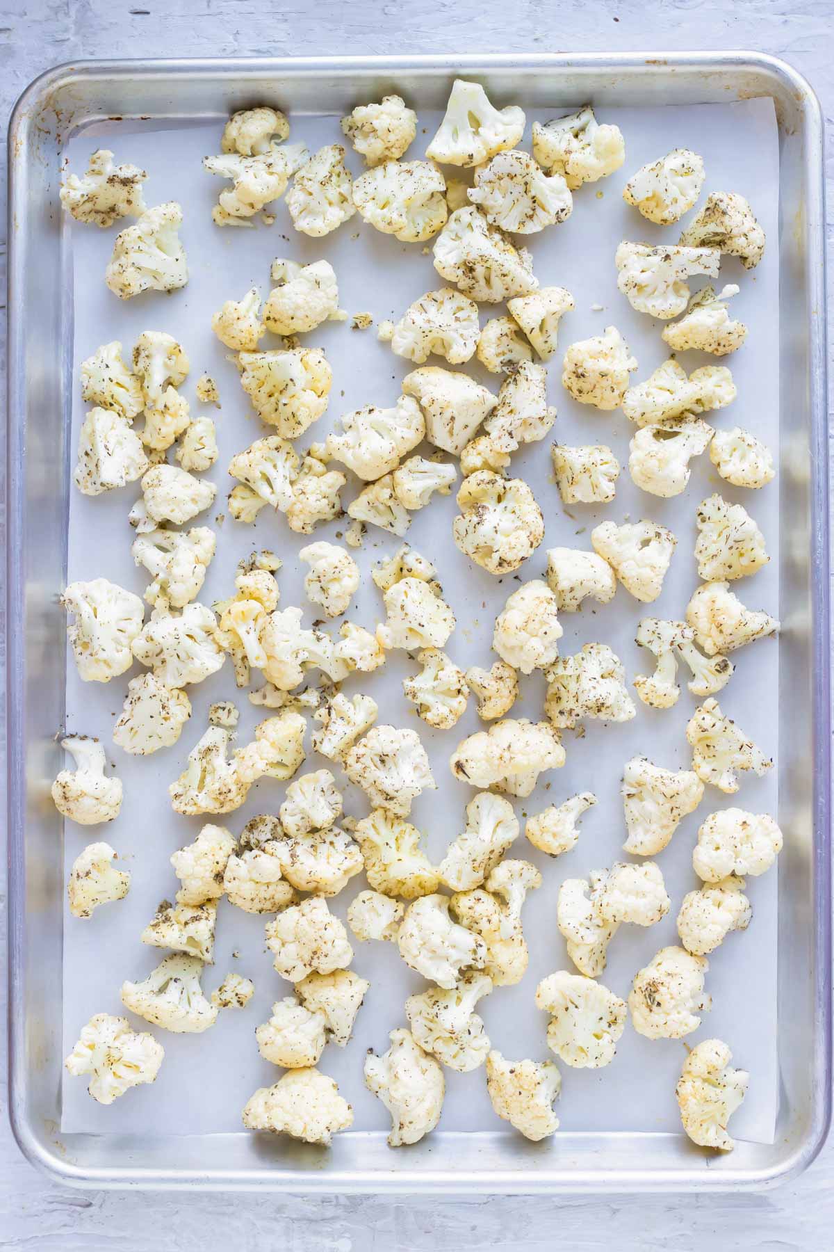 Cauliflower florets on a baking sheet to be roasted in the oven.