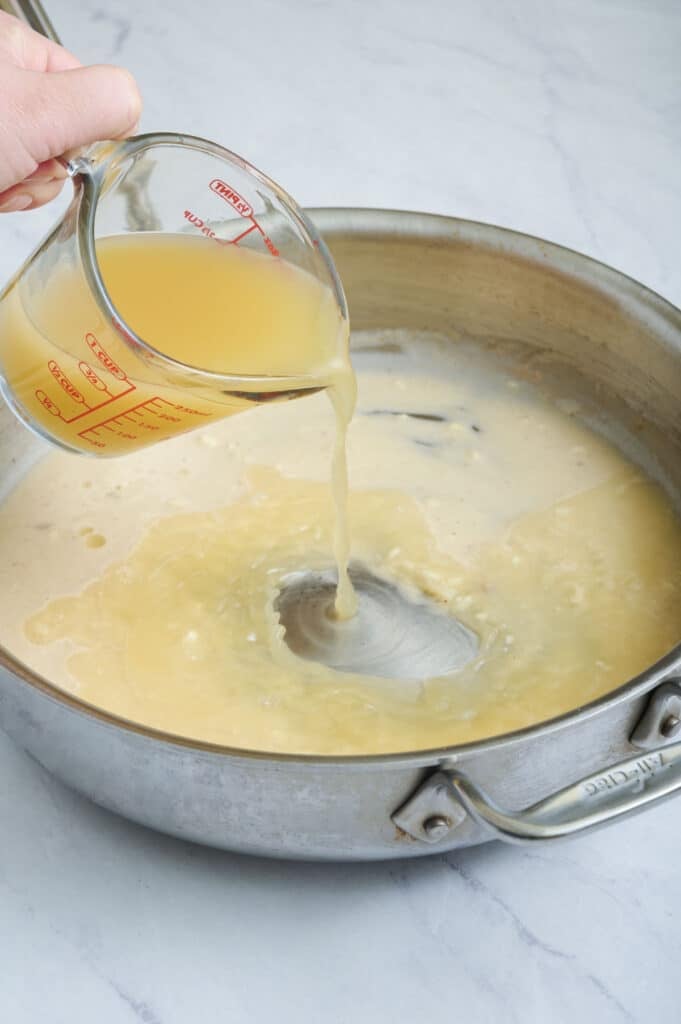 Broth is added in small amounts to make a creamy sauce.