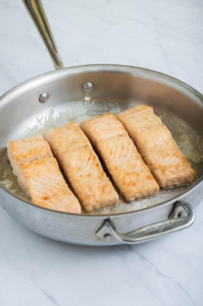 Salmon is flipped to cook on both sides.