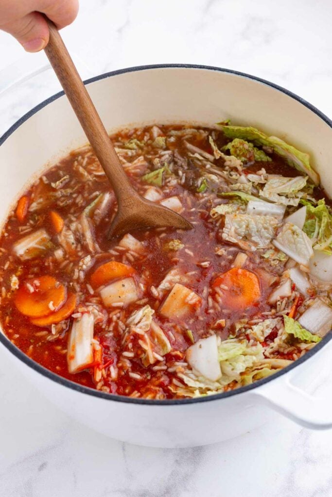 Beef broth is poured into a Dutch oven of make-ahead cabbage roll soup.