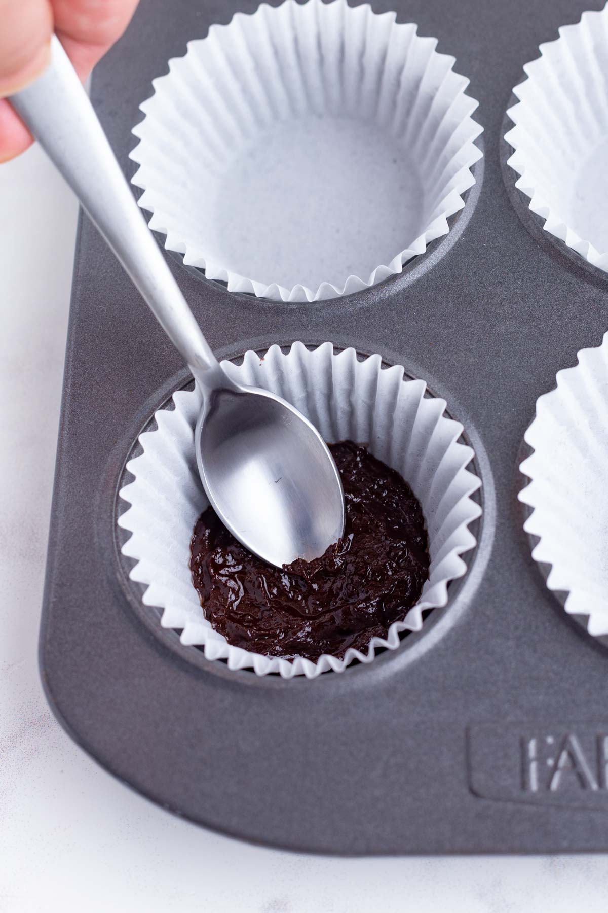 Liquid chocolate is place in the bottom of the muffin liner.