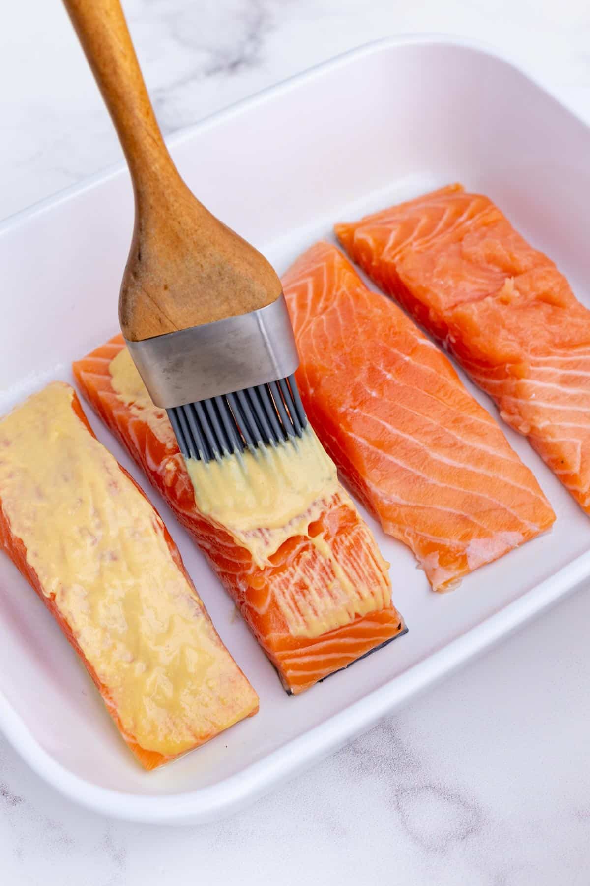 Mustard is brushed over salmon filets.