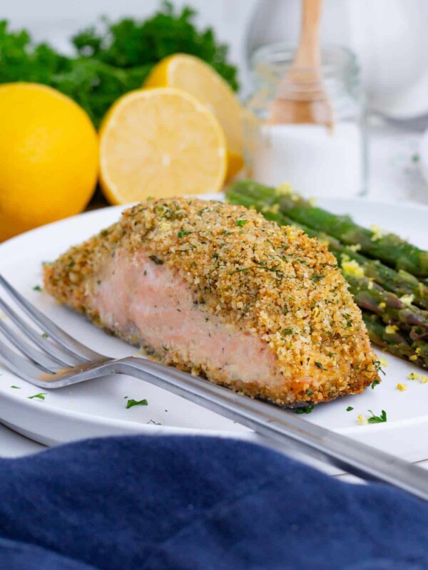 A filet of salmon and asparagus are served with a fork.