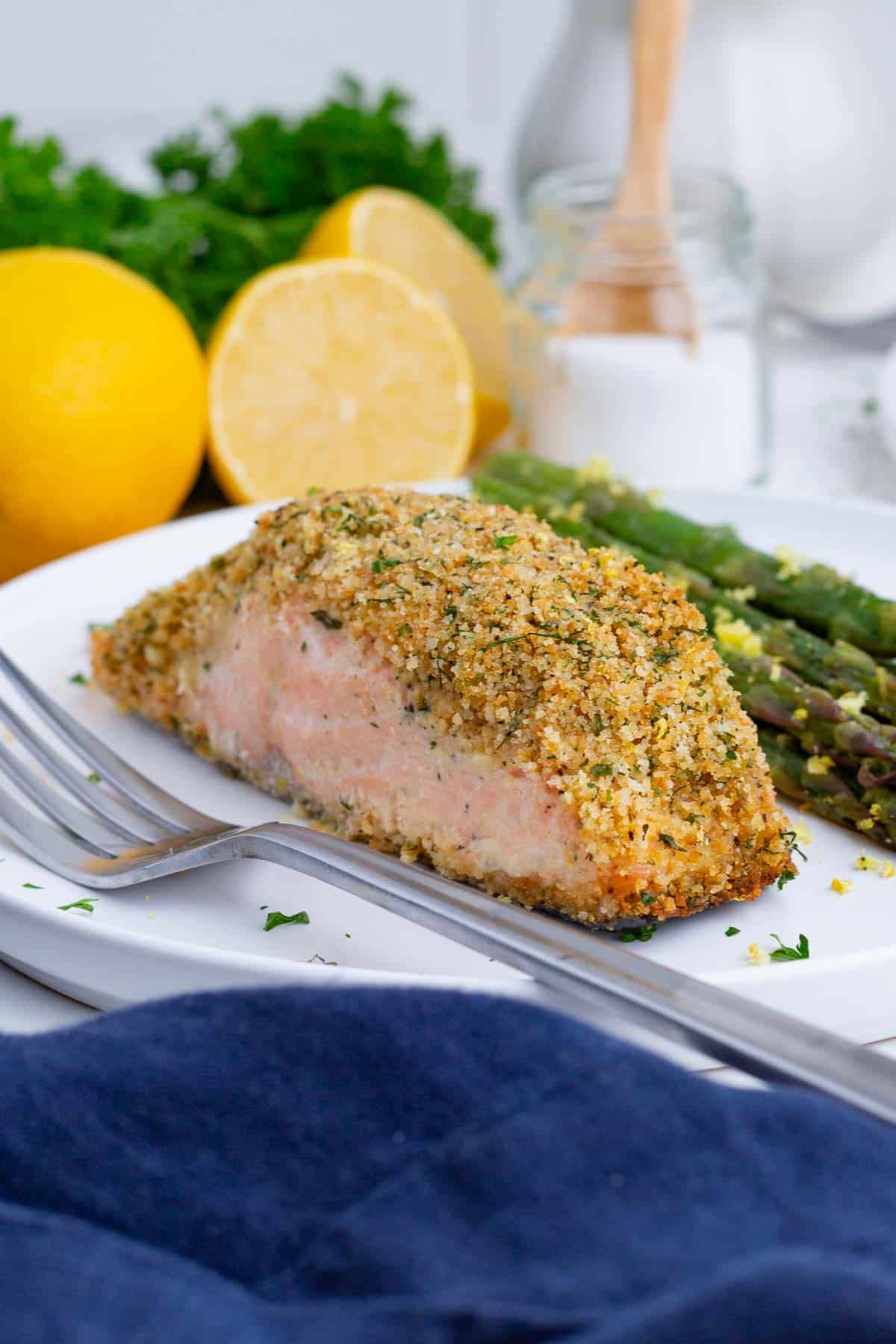 A filet of salmon and asparagus are served with a fork.