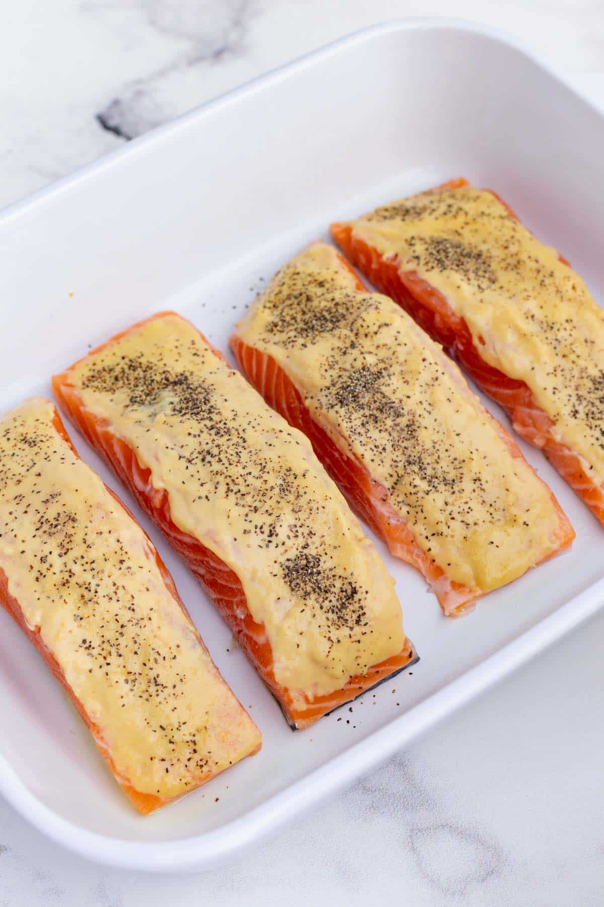 Salt and pepper is sprinkled over the salmon.