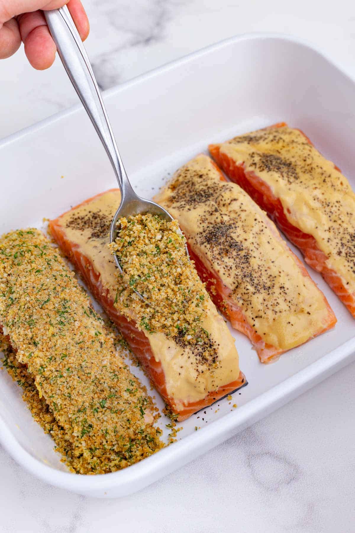 The breadcrumb mixture is placed on top of the salmon filets.